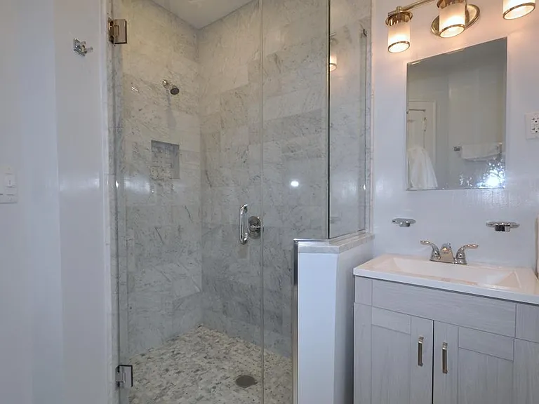 Fully renovated bath with marble tiled step-in shower.