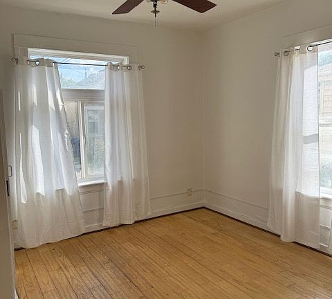 Bedroom with large windows, fan and wood floors