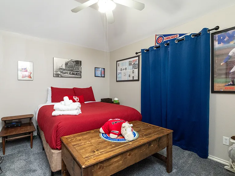 Fun sports-themed bedroom with a comfy queen bed, bold decor, and seating chest. A playful space perfect for kids, teens, or fans looking to relax and unwind.