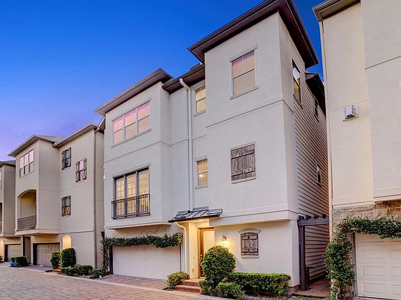 Stucco freestanding three story with two car attached garage on gated street.