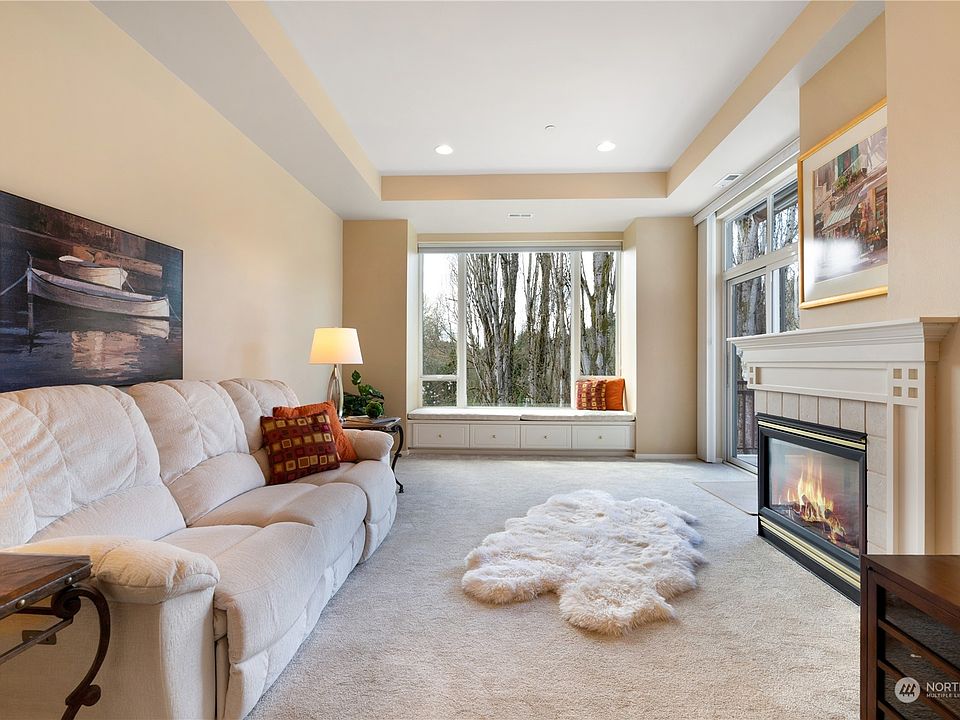 The living room features wall-to-wall carpet, gas fireplace and an incredibly peaceful view overlooking the protected woodlands outside. It is open to the kitchen creating a space for all to connect. Notice the window seat with built-in storage, the coffered ceiling which adds style and flare, and the tall windows that let in all the light! AND notice the air vents in the roof. That's forced air heat and air conditioning!!!>