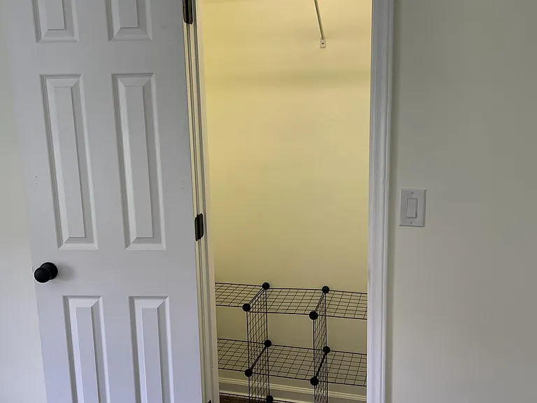 Dedicated storage closet with hanging rod, top shelf, and wire shelving for easy organization of clothing and essentials.