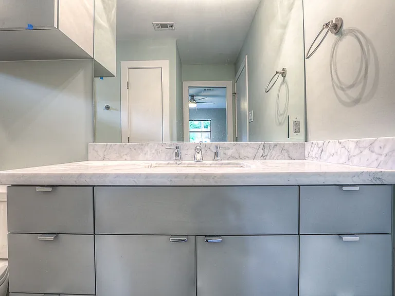 Detailed view of the guest bath vanity _ Carrara marble counter, undermount sink, modern chrome fixtures, and full-width mirror