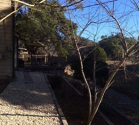 Back side yard leading to step down garden beds to creek bed