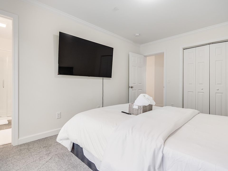 Private bedroom with wall-mounted TV, plush carpet, and sliding-door closet, plus convenient access to an adjacent bath.
