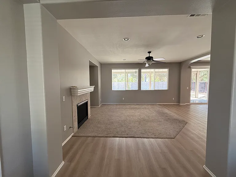 Downstairs entryway/living room. Big windows, lots of light, large sliding glass doors to outdoor covered patio. Ceiling fan.