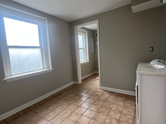 View from bathroom looking into laundry room with washer dryer hookup and additional clothes hanging area . Windows now have new privacy blinds installed.