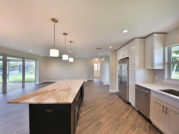 Kitchen features white wood cabinets, Carrara Marble countertops, Samsung appliances, glass backsplash & large island.