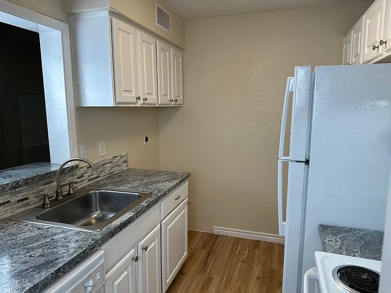 Modern kitchen with sleek countertops, stainless steel sink, and ample white cabinetry, offering a functional and stylish culinary space. Modern kitchen with sleek countertops, stainless steel sink, and ample white cabinetry, offering a functional and sty