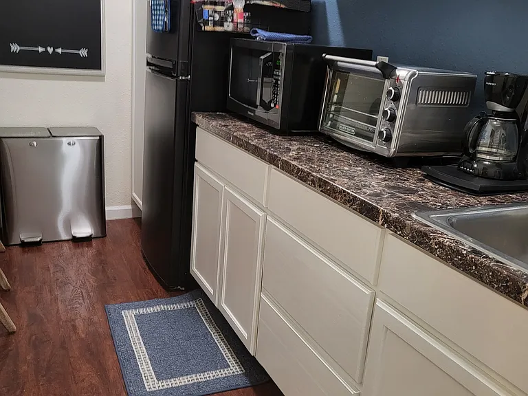 Basement Kitchenette w/full sized refrigerator, microwave, toaster oven, toaster, coffee pot, electric kettle, crockpot, plates, glasses, utensils.