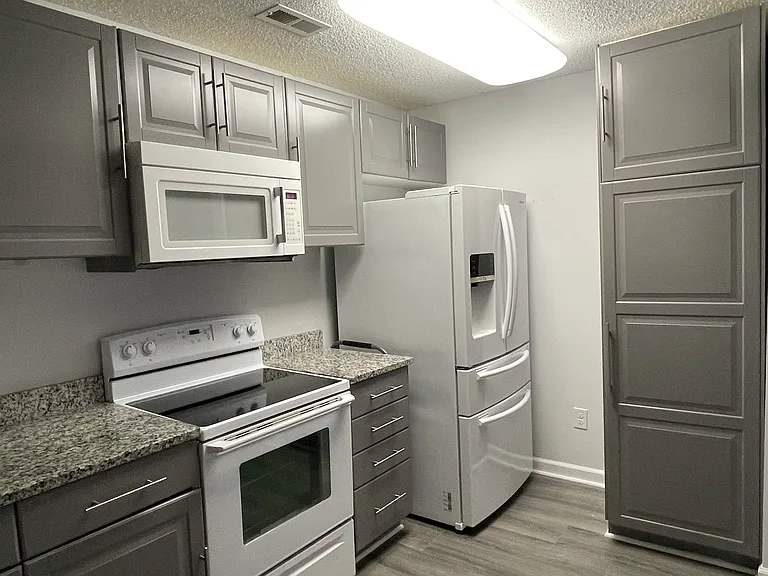 This view of the kitchen shows the large storage cabinet and the large refrigerator with ice and water dispenser.