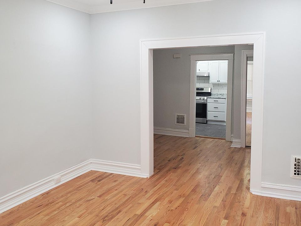 Partial view of Front room looking back into apartment. New ceiling fan, hardwood floors, decorative fireplace.