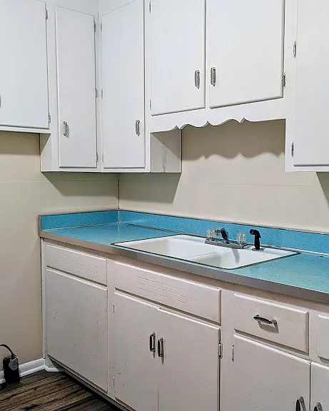 The laundry room features cabinetry and a sink.