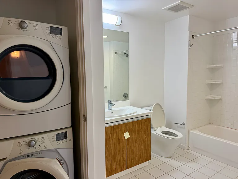 Full size bathroom with shower/tub, washer/dryer and storage under sink.