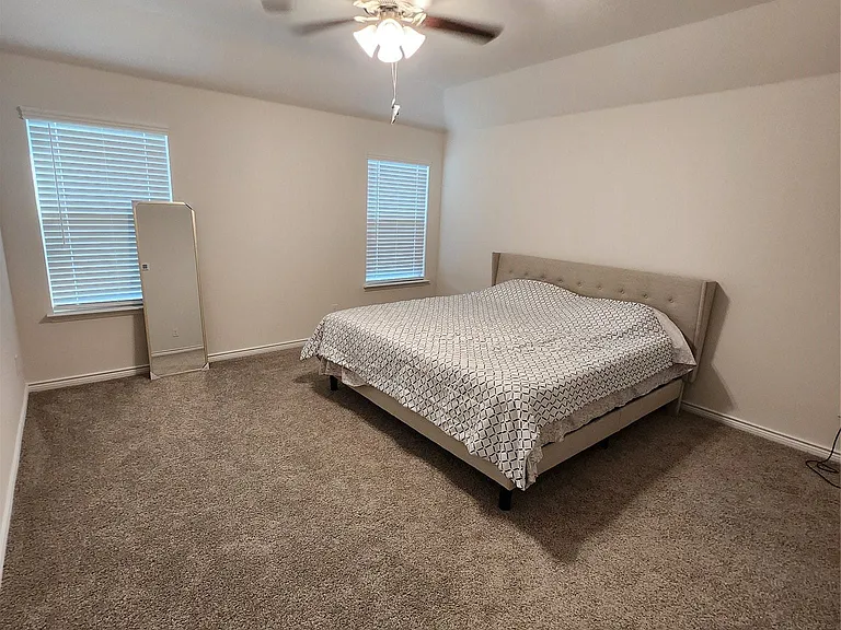 Spacious room featuring neutral carpeting, a ceiling fan with integrated lighting, and white walls