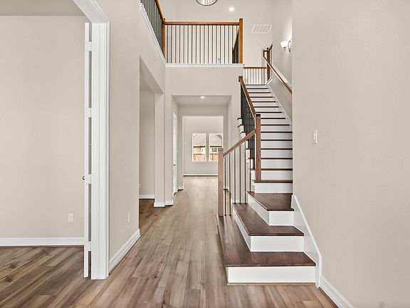The two story entryway features a modern chandelier and grand staircase with rod iron spindles