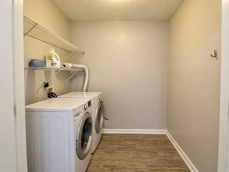 Dedicated laundry room with side-by-side washer and dryer, wire shelving, and durable flooring for easy upkeep.