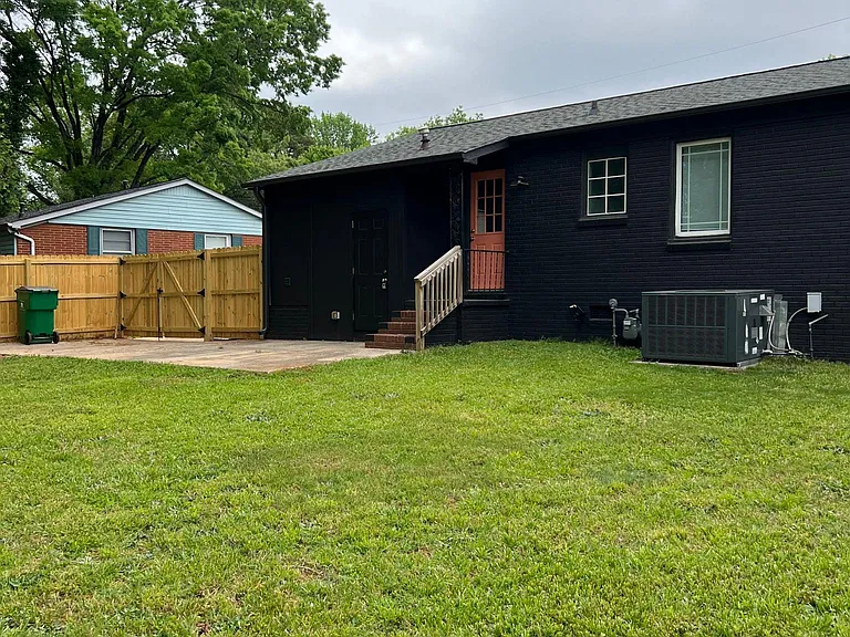 Rear entry of home leads to a concrete patio and the expansive yard