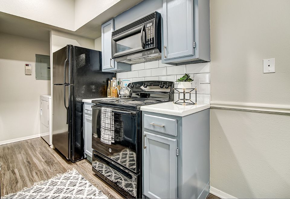Kitchen with subway tile back-splash, faux-wood floors, and black appliance package