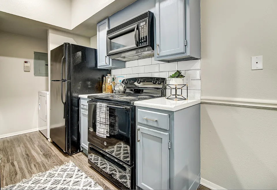 Kitchen with subway tile back-splash, faux-wood floors, and black appliance package