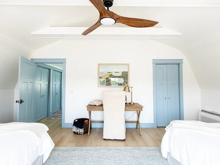 The second bedroom includes two full beds, two small dressers, a closet, a desk, and French doors that open out to the expansive back deck that overlooks vineyards.
