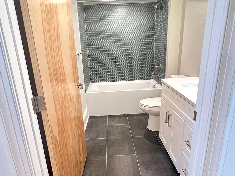 En-suite bathroom with tub/shower, large format porcelain tile on the floor, hex wall tile in tub/shower.