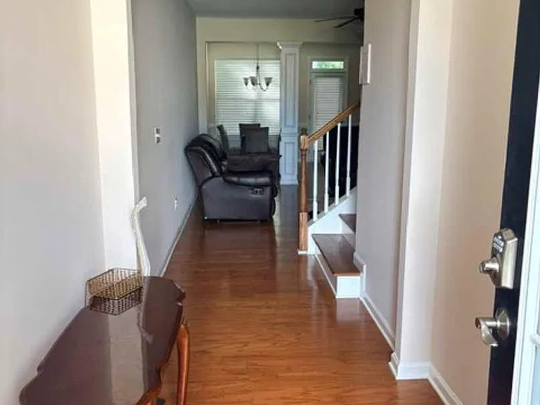 Entry hall with hardwood floors, arched doorway, staircase access, and a sitting area near the front windows.