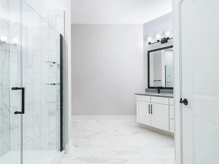 Designer bathrooms with quartz countertops and frameless glass showers.