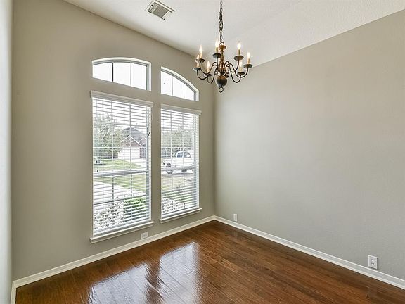Dining room located to the left of the entry with views to the front of home, wood flooring and a tasteful candelabra light fixture.