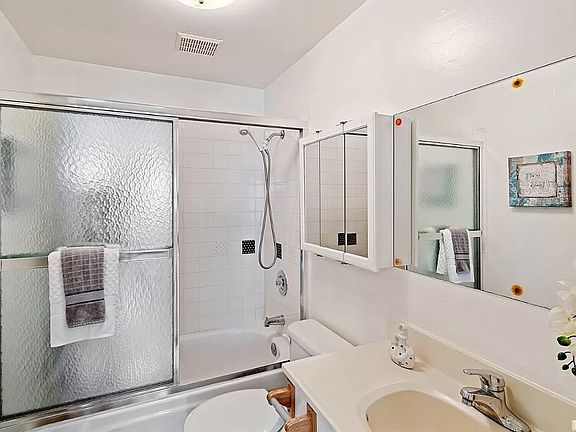 Clean, well-lit bathroom, with shower over full bath tub.