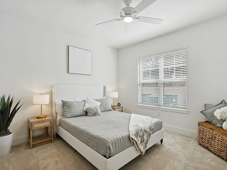 Bright and inviting bedroom with a cozy queen-sized bed, elegant decor, and natural light streaming through large windows.