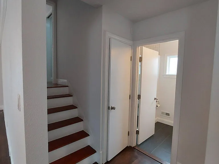 Hall with bath 1, stairs to bed 1 and door to garage