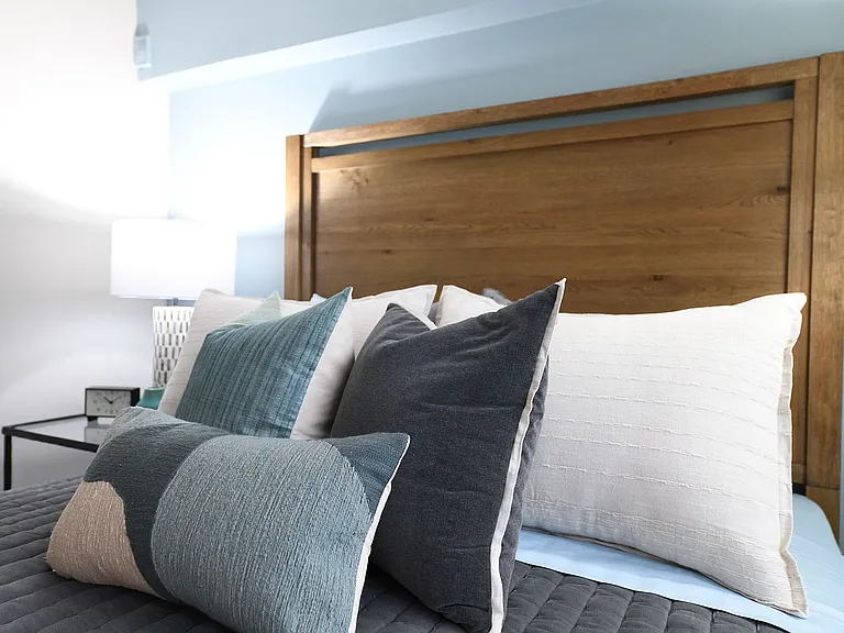 Experience restful nights in this elegantly designed bedroom featuring warm wood tones and soft textures.