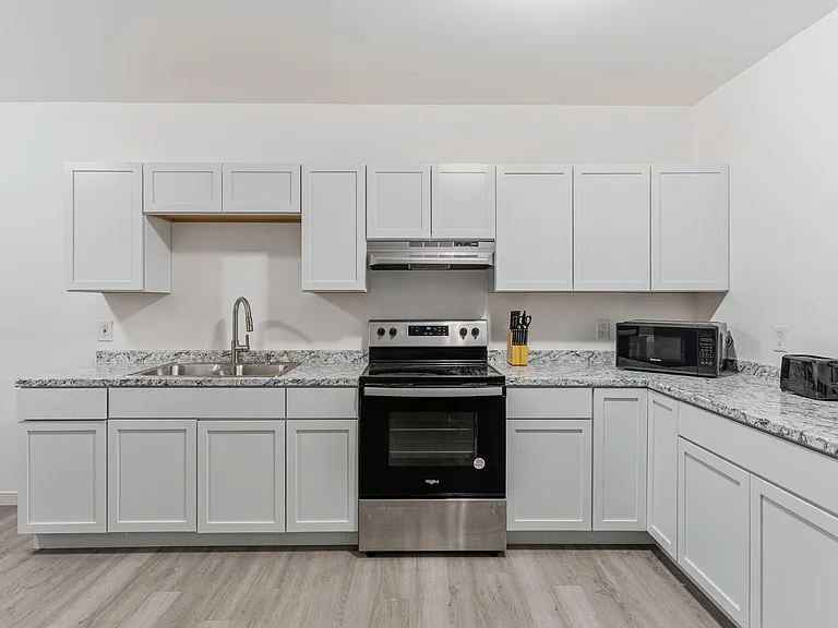 Spacious U-shaped kitchen with shaker cabinets, granite-look counters, double sink, and full-size range with hood.