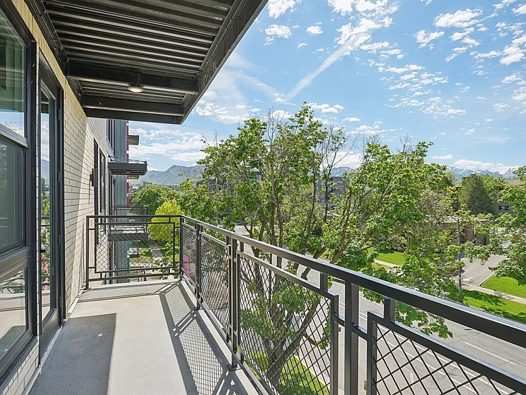 Liberty Duet Apartments, Salt Lake City, Utah; A balcony with a metal railing overlooks a street and trees.