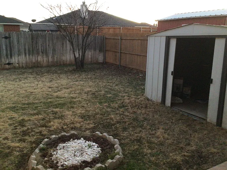 Fenced backyard with storage building