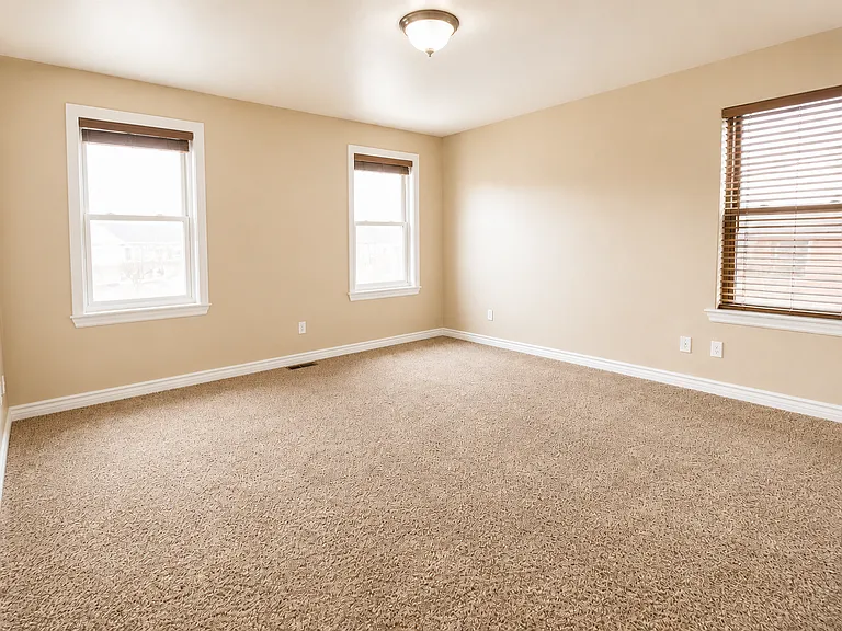 Spacious primary bedroom with three windows and plenty of natural light.