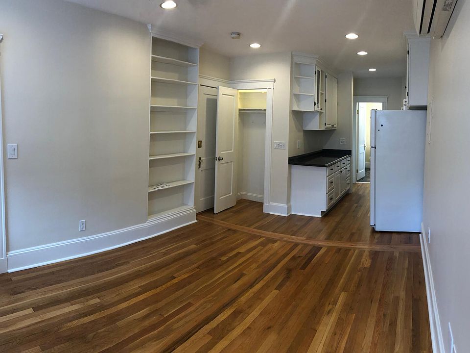 View from living room into kitchen. Coat closet door is open. Apartment entrance door and built in bookcase to the left. Designated office located to the far left.