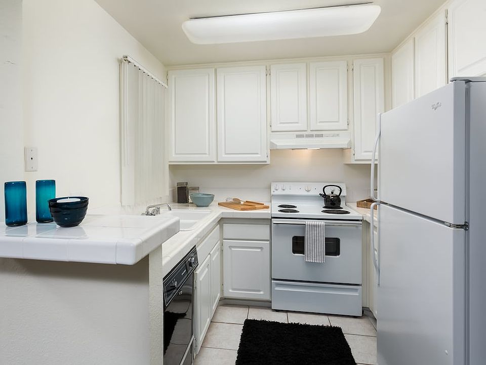 Classic kitchen with white tile countertops, white cabinetry, white appliances, and tile flooring