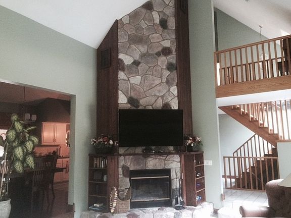 Living Room : Stone fire place with maple mantle. Vaulted ceiling with fan. Wall of windows.