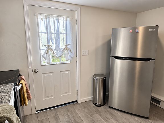 Full-size new stainless-steel refrigerator and easy access to the backyard and deck.