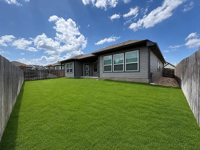 Backyard with patio and river rock along both sides of the home