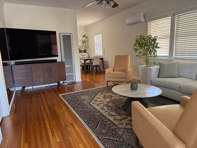 Spacious living room with air-conditioning, fan, natural light.