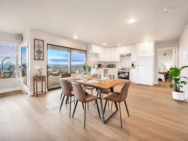 A bright and airy living space featuring a cozy dining area, a sleek kitchen with pretty accents_perfect for enjoying meals with a view. Large windows bring in plenty of natural light!