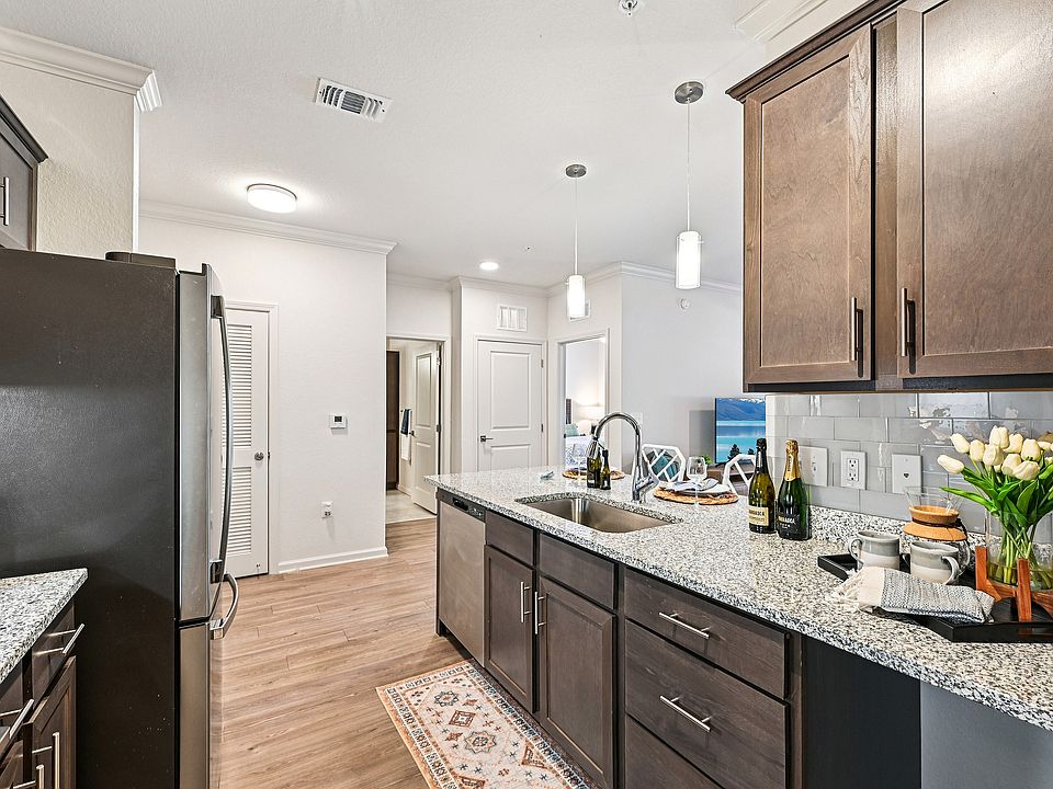 Modern kitchen with sleek granite countertops, stylish dark cabinets, and elegant pendant lighting, creating a welcoming space for cooking and entertaining.