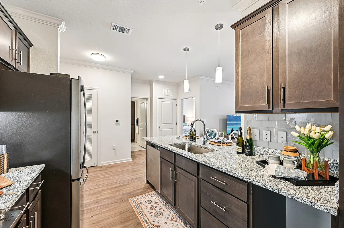Modern kitchen with sleek granite countertops, stylish dark cabinets, and elegant pendant lighting, creating a welcoming space for cooking and entertaining. - The Sovana at Stuart