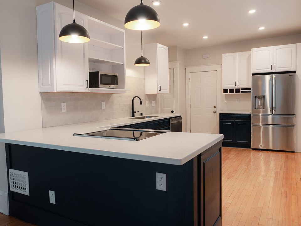 Kitchen with beautiful Spanish tile for backsplash and solid surface countertops. The kitchen includes stainless steel applicances: fridge, dishwasher, microwave and stove.