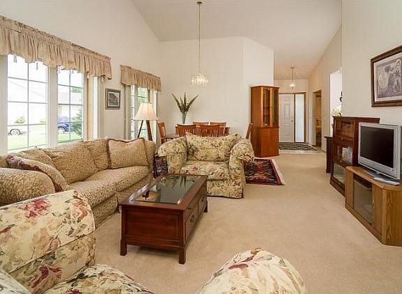 The living room has high vaulted ceilings and large windows, letting in tons of natural light across