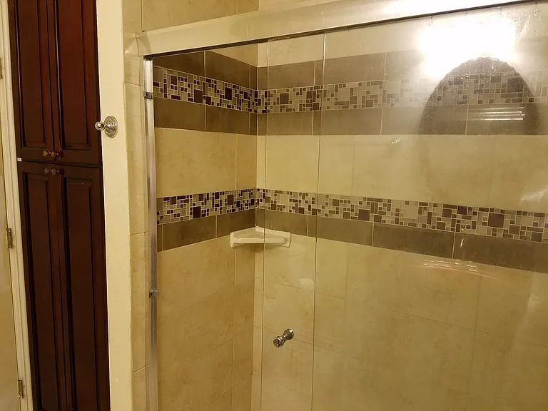 Front bathroom step in shower and cabinets storage.