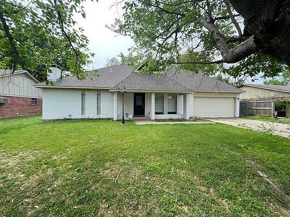Ranch-style home with a front lawn, driveway, an attached garage, and brick siding